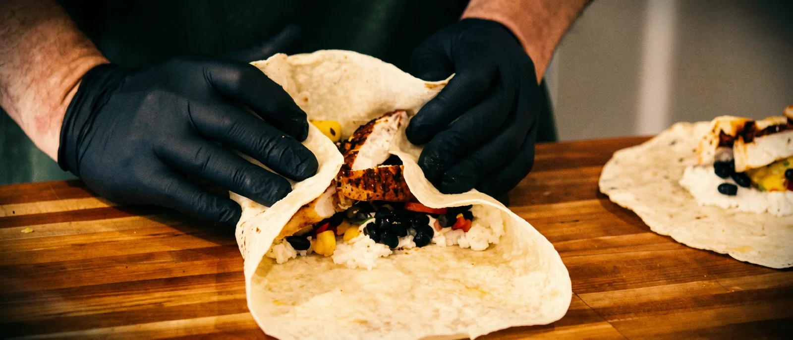 Chef T folding a fresh chicken wrap
