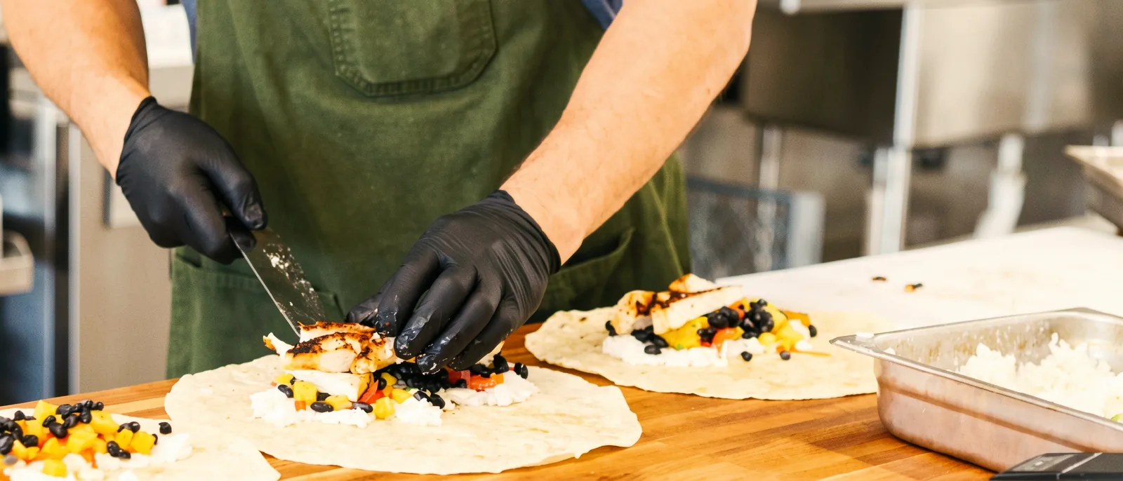Chef T slicing blackened chicken onto tortillas in The Fix kitchen