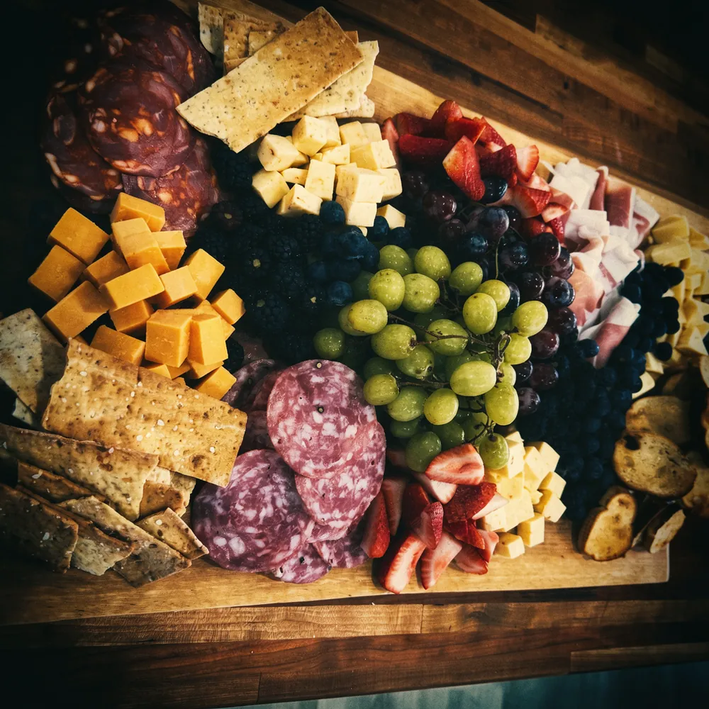 A loaded charcuterie board with meats, cheeses, and fresh fruit