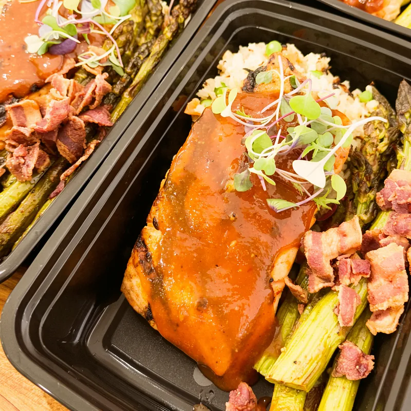 Glazed salmon over cauliflower rice with roasted asparagus, packed fresh in a meal-prep tray