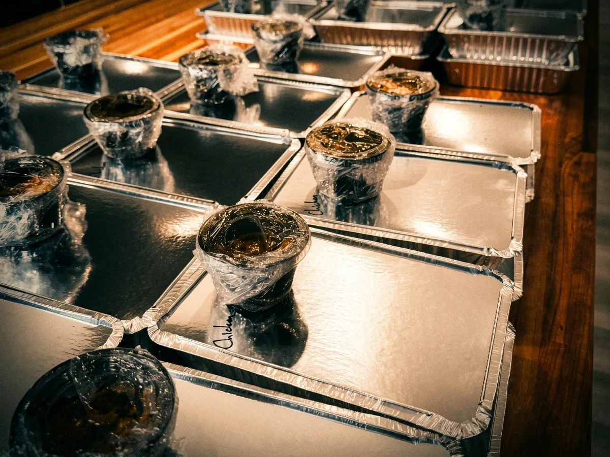 Labeled foil to-go trays lined up fresh from the kitchen